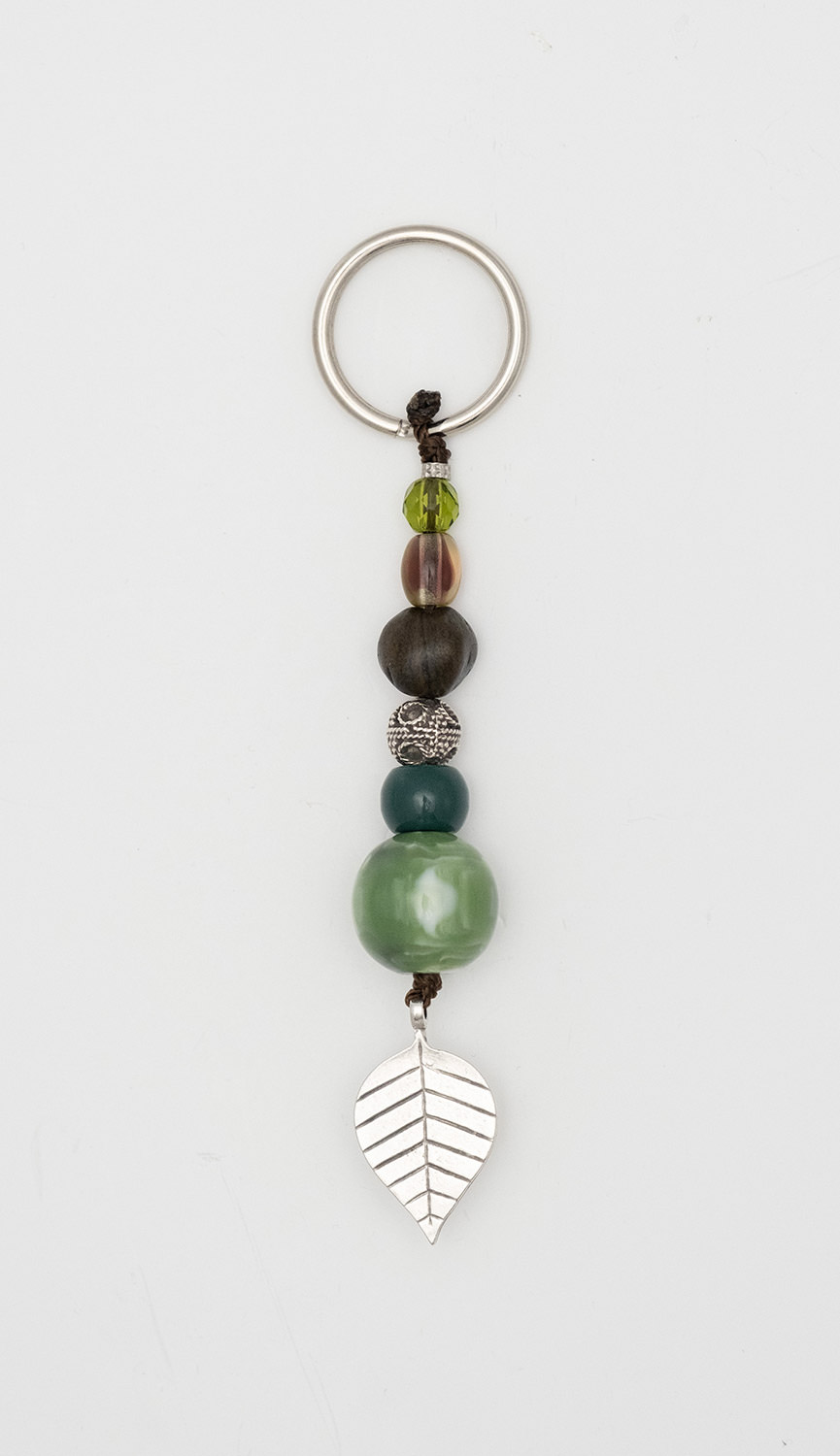 Keyring made of artificial resin, crystal and conifer seed with a leaf